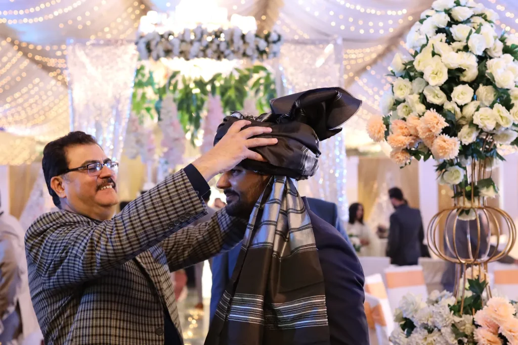 Umar Hameed’s father adjusting the turban on his head at his wedding, Nov 2022