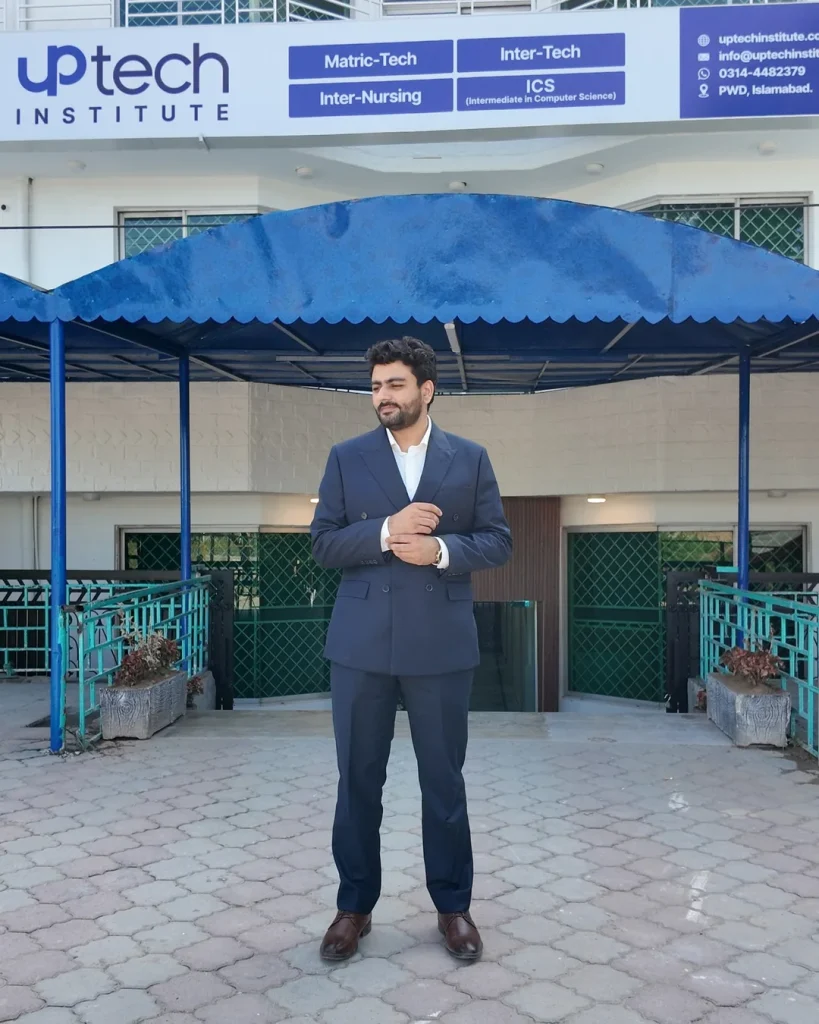 Umar Hameed in a navy suit standing in front of the Uptech Institute building entrance under a blue canopy